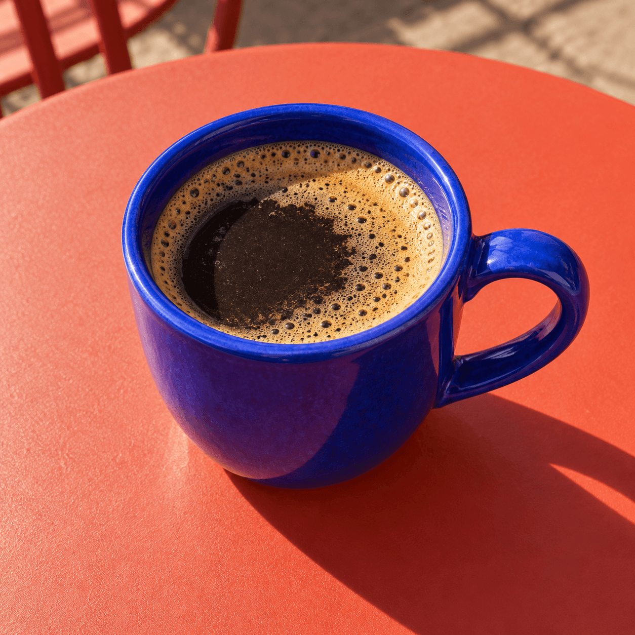 A blue coffee cup casting a long shadow on a coral table